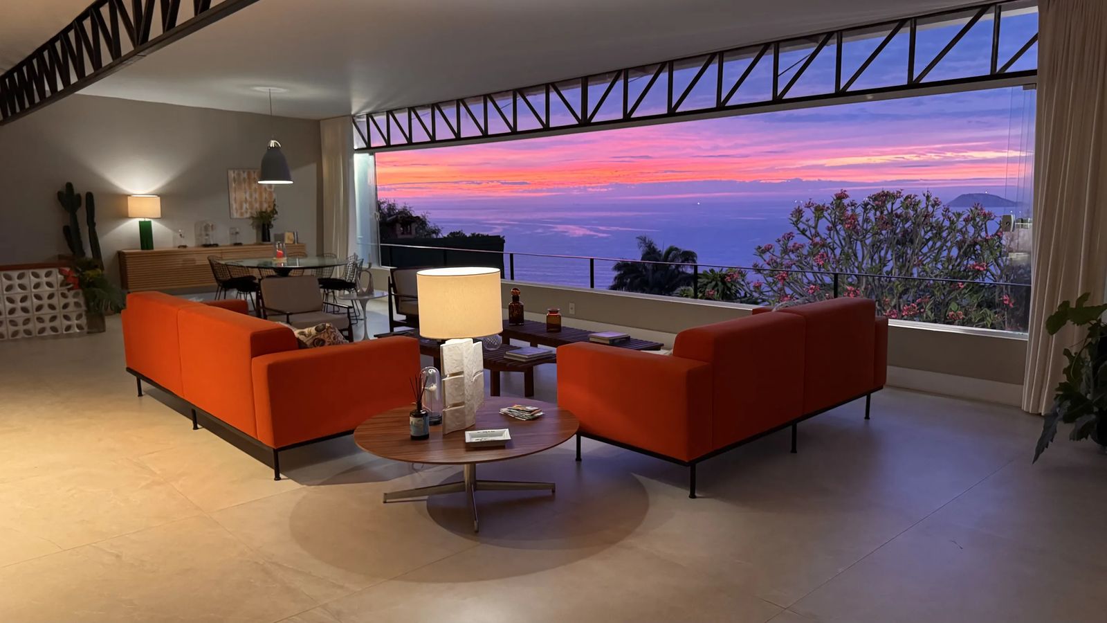 Lever de soleil sur l'océan depuis le salon de Vila Oriba, canapés orange et baie ouverte